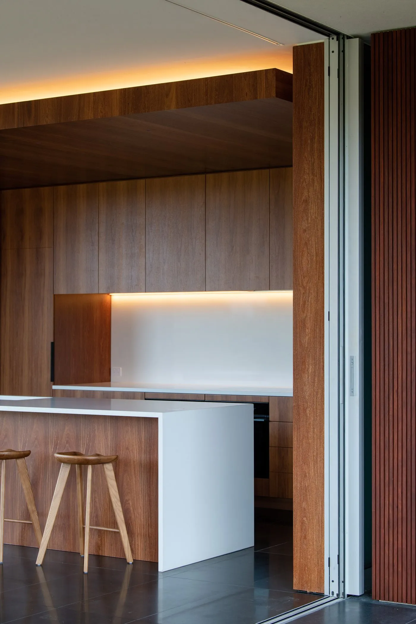 Timber-lined kitchen with a white stone bench