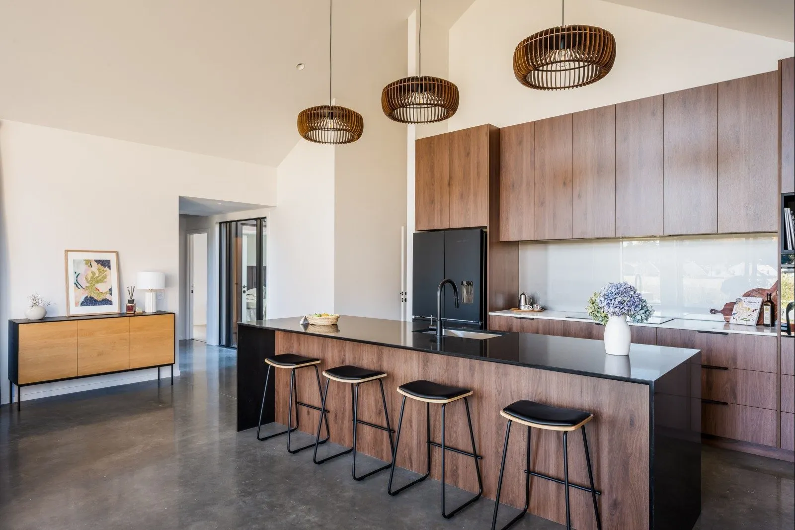 Walnut kitchen with a black stone island under timber pendants